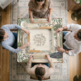Square mahjong mat with a cream background, sage green cranes, bamboo leaves, peony branches, stones, and thin linework.