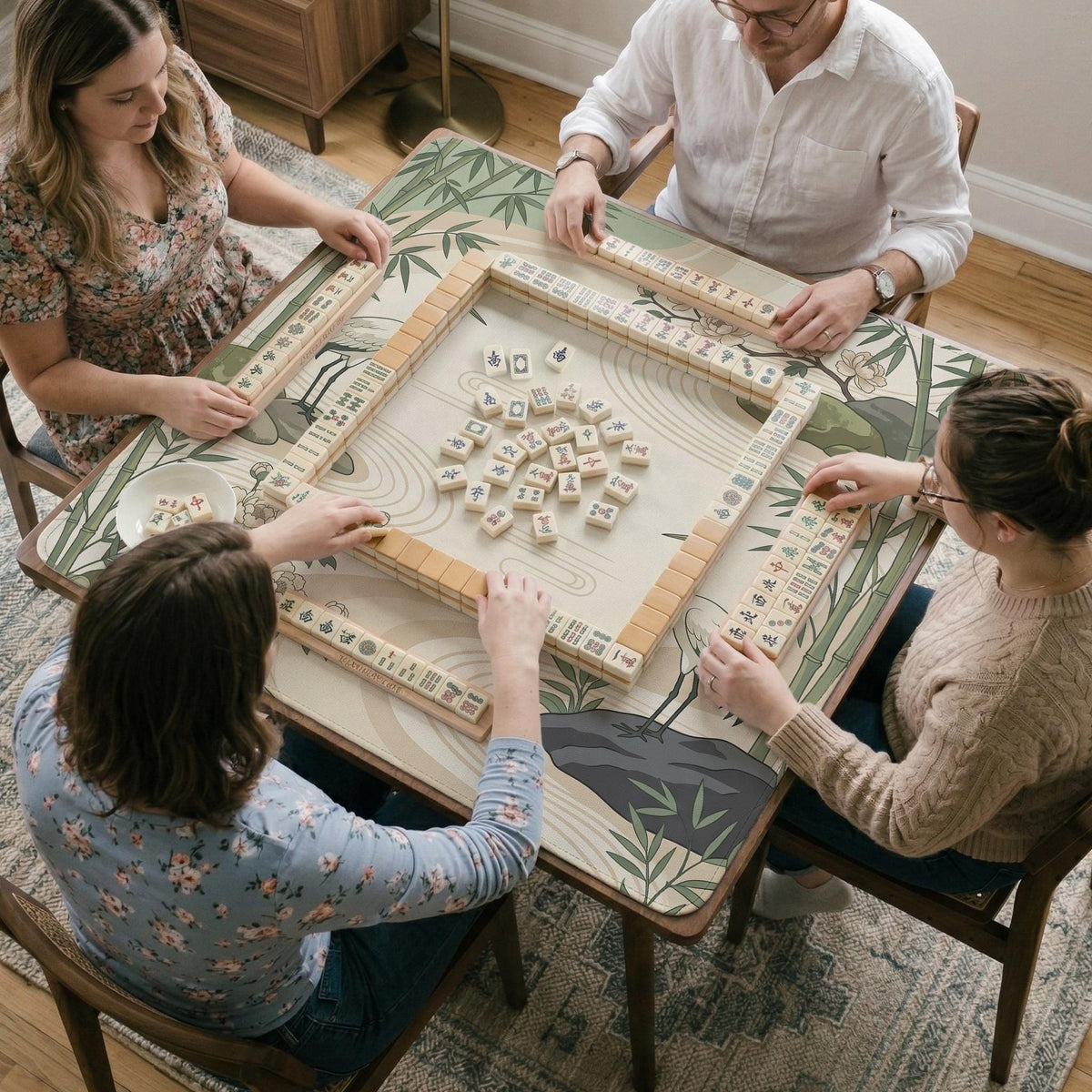Square mahjong mat with a cream background, sage green cranes, bamboo leaves, peony branches, stones, and thin linework.