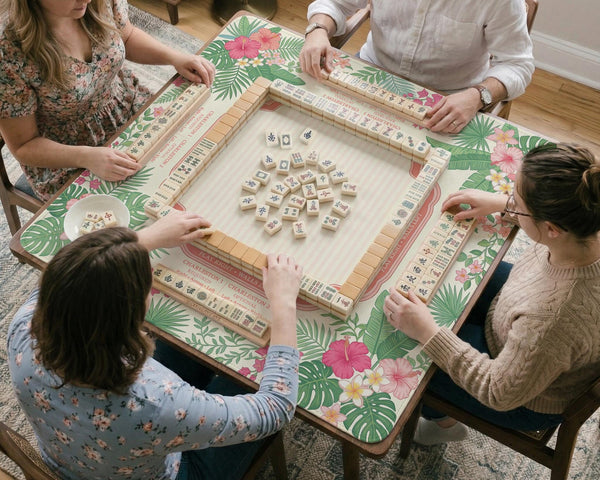 Coral tropical floral mahjong mat with hibiscus flowers, palm leaves, cream sections, and a scalloped edge.