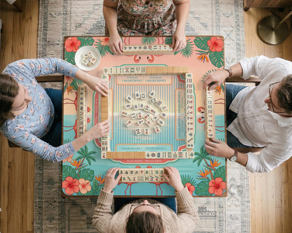 Pink mahjong mat with flamingos, palm leaves, hibiscus flowers, and aqua tropical background.