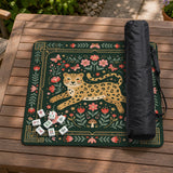 Dark green square mahjong mat with a golden spotted leopard in the center, surrounded by flowers, leafy stems, butterflies, and small star accents.