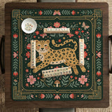 Dark green square mahjong mat with a golden spotted leopard in the center, surrounded by flowers, leafy stems, butterflies, and small star accents.