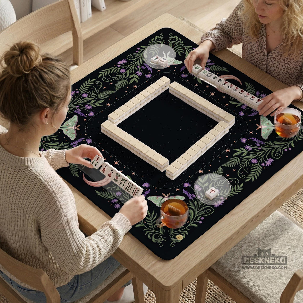 Black mahjong table mat with luna moths, purple flowers, soft green leaves, copper moons, and small star details.