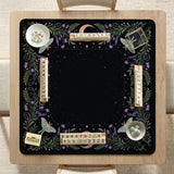 Black mahjong table mat with luna moths, purple flowers, soft green leaves, copper moons, and small star details.