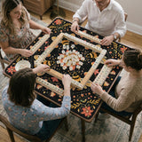 Black mahjong mat with a symmetrical botanical design, coral flowers, golden leaves, and small bees.