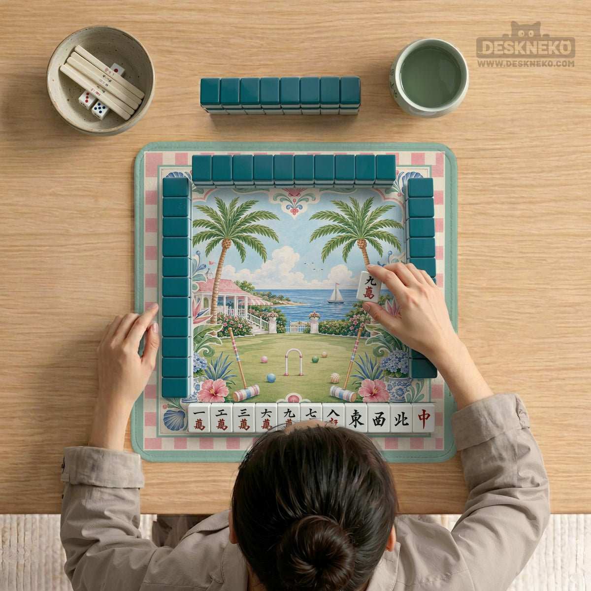 Pastel mahjong mat with a pink gingham border, seashells, hydrangea pots, palm trees, croquet details, and a coastal garden scene.