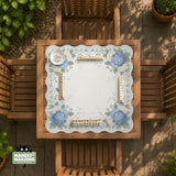 A square blue mahjong mat with hydrangea flowers, cream blossoms, sage leaves, and vines around a plain center play area. The edge is scalloped.