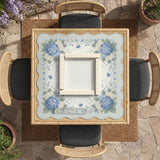 A square blue mahjong mat with hydrangea flowers, cream blossoms, sage leaves, and vines around a plain center play area. The edge is scalloped.