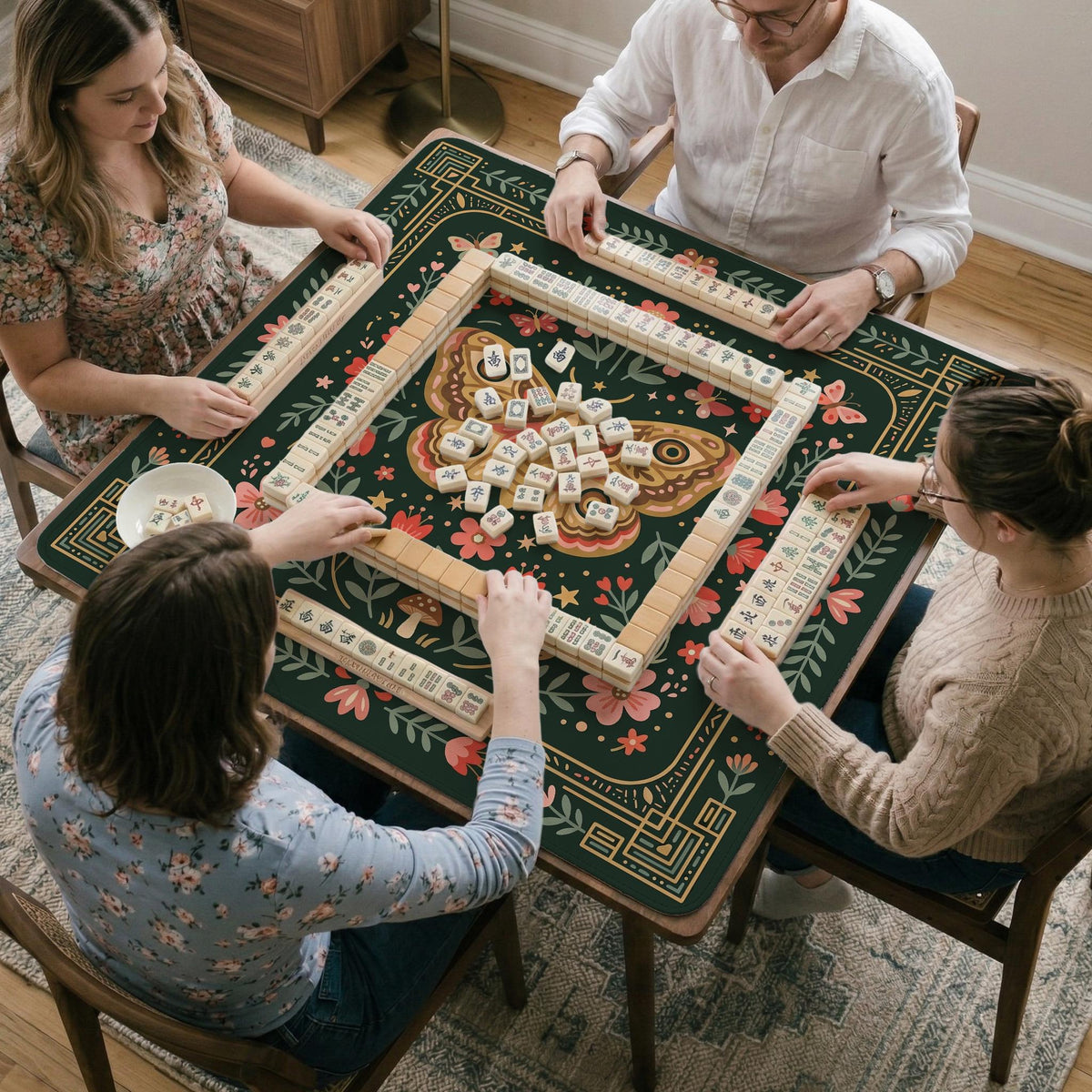 Dark green square mahjong mat with floral branches, small red blossoms, gold line details, and a large moth in the center.