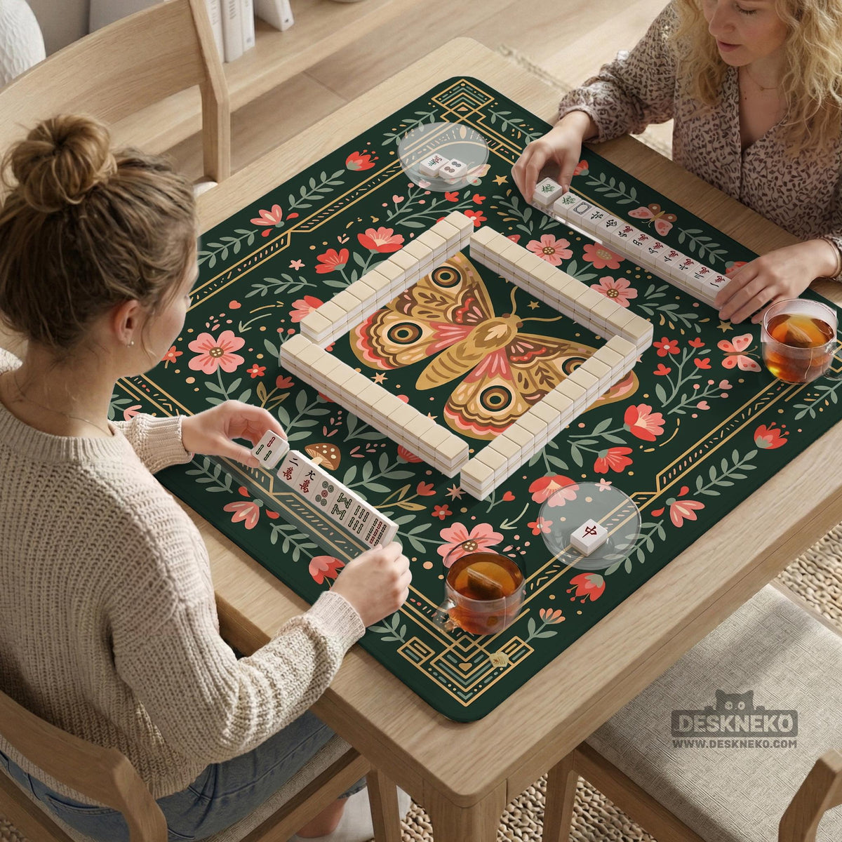 Dark green square mahjong mat with floral branches, small red blossoms, gold line details, and a large moth in the center.