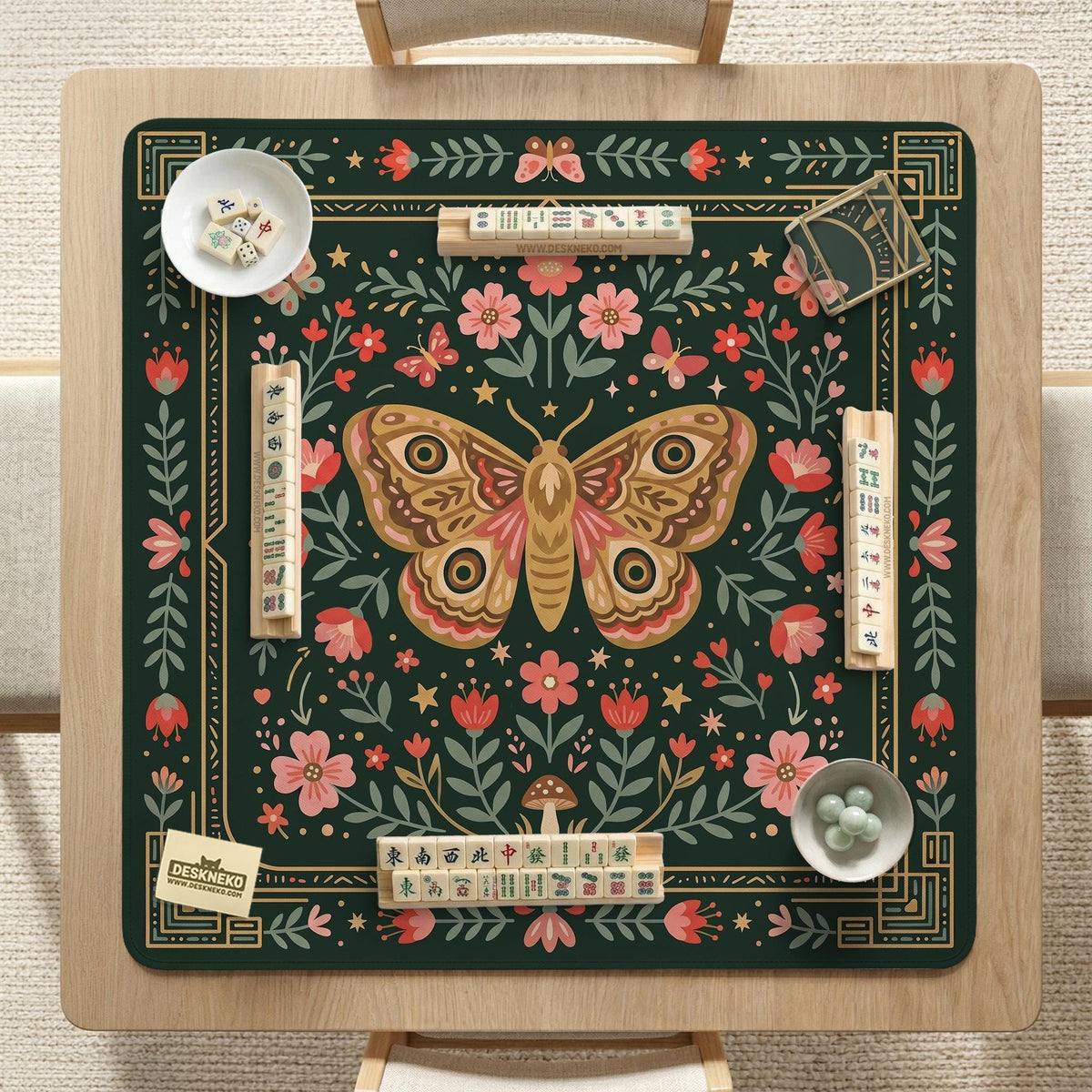 Dark green square mahjong mat with floral branches, small red blossoms, gold line details, and a large moth in the center.