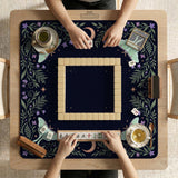 Navy square mahjong mat with a floral border, copper moons, scattered stars, pale moths, and leafy botanical details.