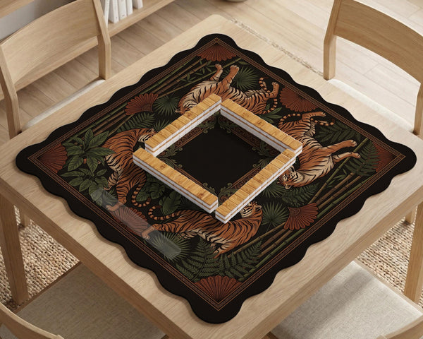 Black square mahjong mat with mirrored tiger faces, bamboo, dark tropical leaves, ornate border details, and orange accents.