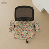 Cream desk chair cover with a vintage floral print featuring coral roses, mustard daisies, and green vines on a chair.