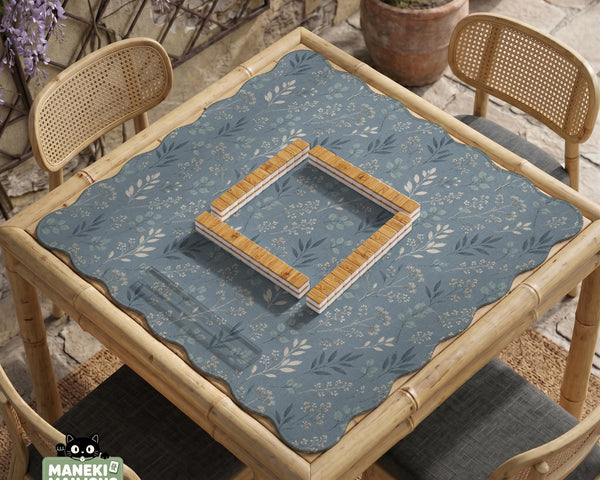 Blue mahjong mat with a dusty linen-look background and small leafy botanical stems in a floral pattern.