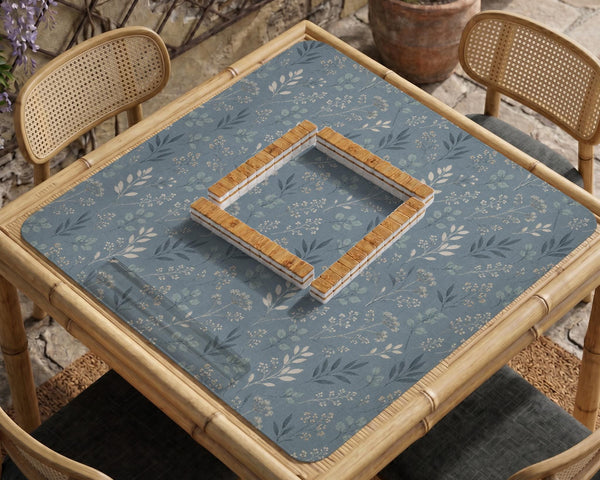 Blue mahjong mat with a dusty linen-look background and small leafy botanical stems in a floral pattern.