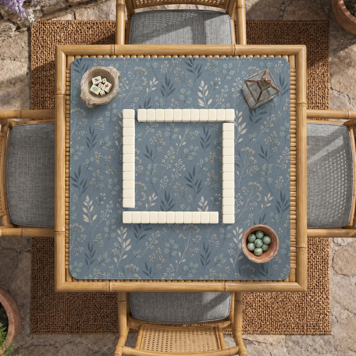 Blue mahjong mat with a botanical floral pattern, pale leaves, and delicate stems on a dusty blue background.