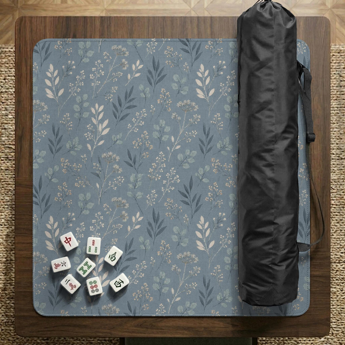 Blue mahjong mat with a botanical floral pattern, pale leaves, and delicate stems on a dusty blue background.