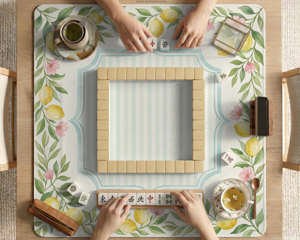 Square yellow mahjong mat with a citrus garden border, green vines, pink blossoms, aqua accents, and a plain center play area.
