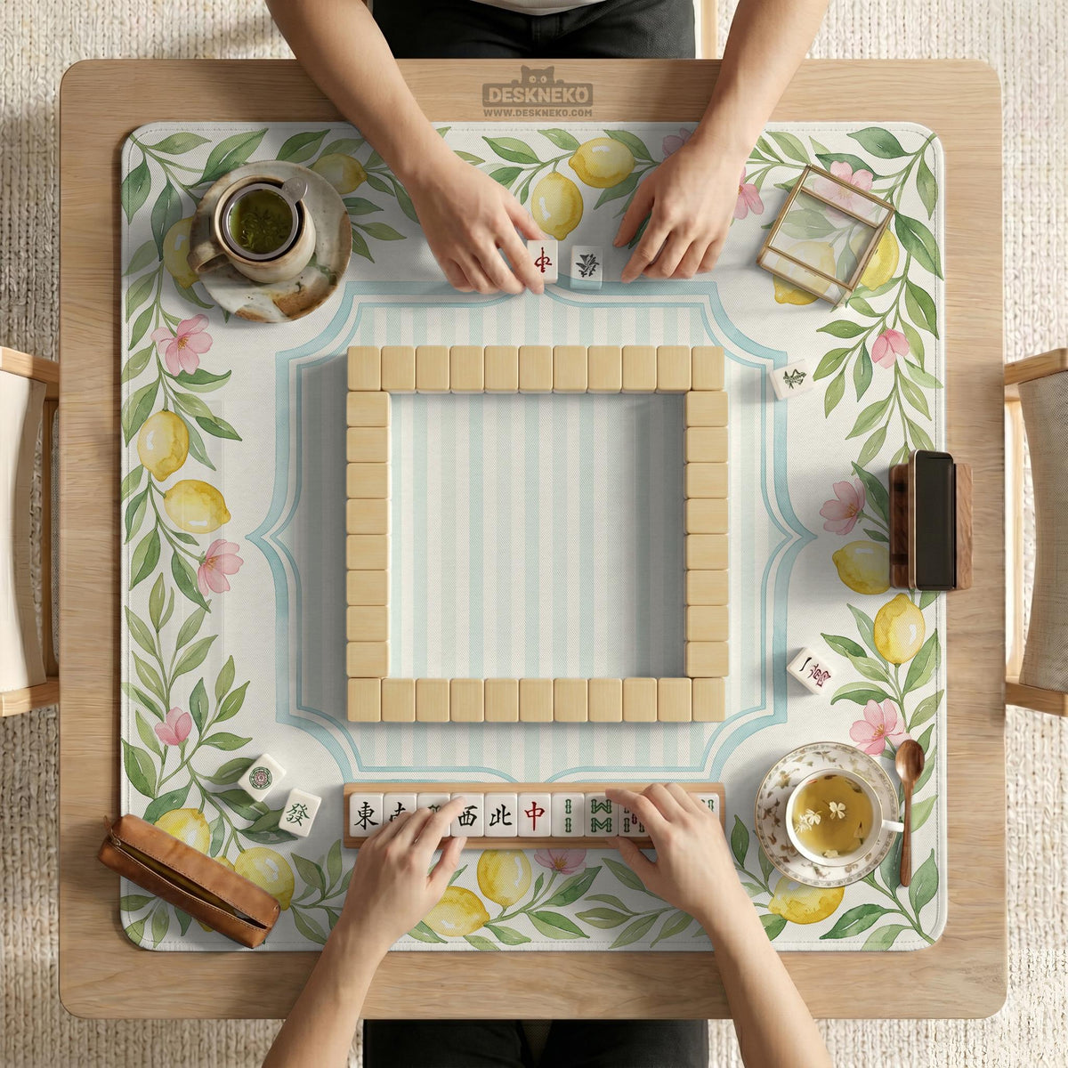 Square yellow mahjong mat with a citrus garden border, green vines, pink blossoms, aqua accents, and a plain center play area.