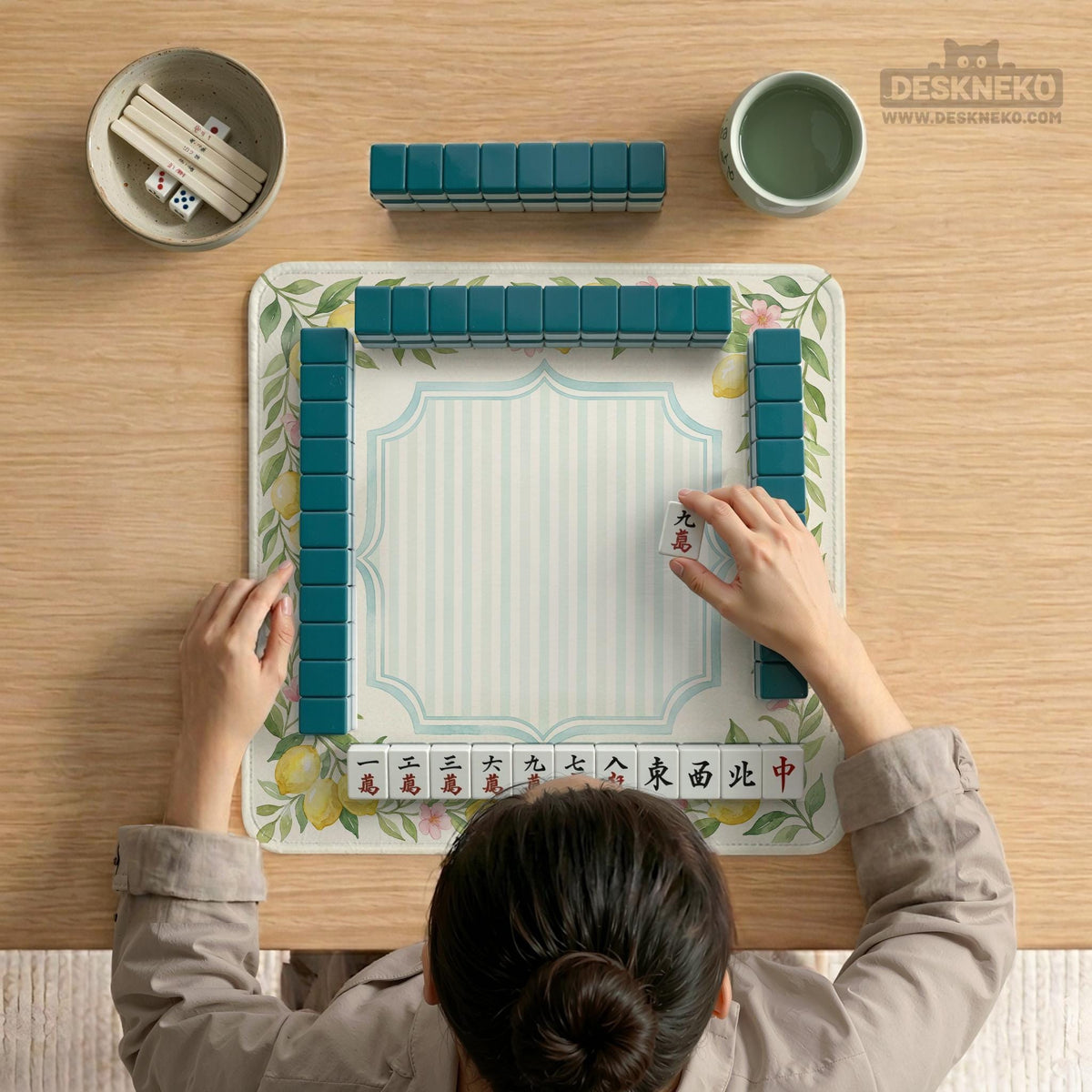 Square yellow mahjong mat with a citrus garden border, green vines, pink blossoms, aqua accents, and a plain center play area.