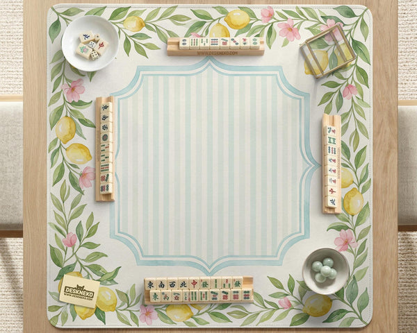 Square yellow mahjong mat with a citrus garden border, green vines, pink blossoms, aqua accents, and a plain center play area.