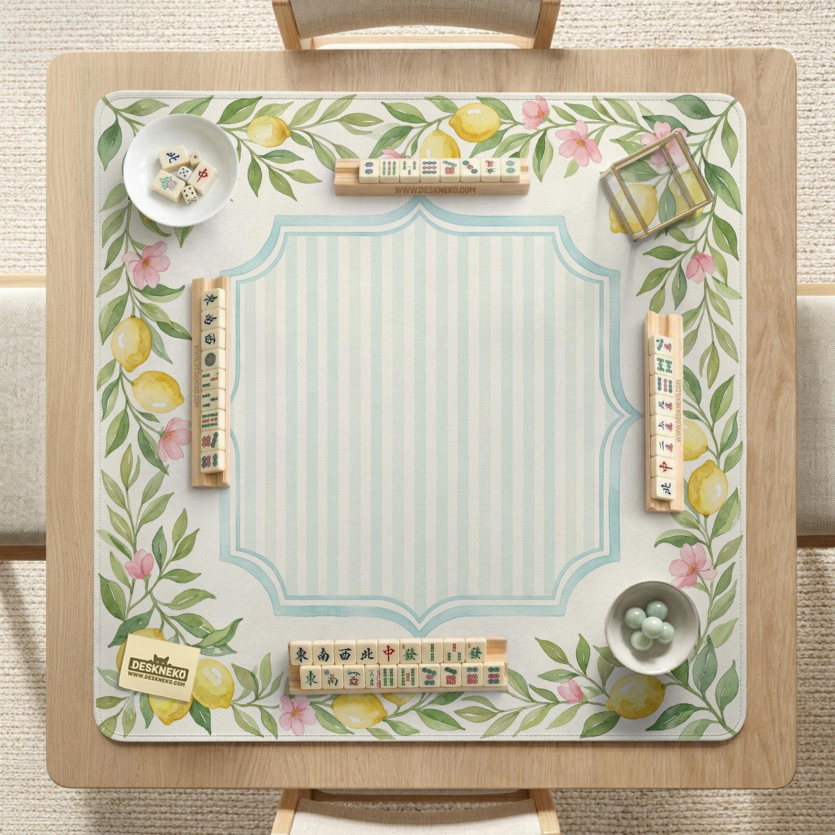 Square yellow mahjong mat with a citrus garden border, green vines, pink blossoms, aqua accents, and a plain center play area.