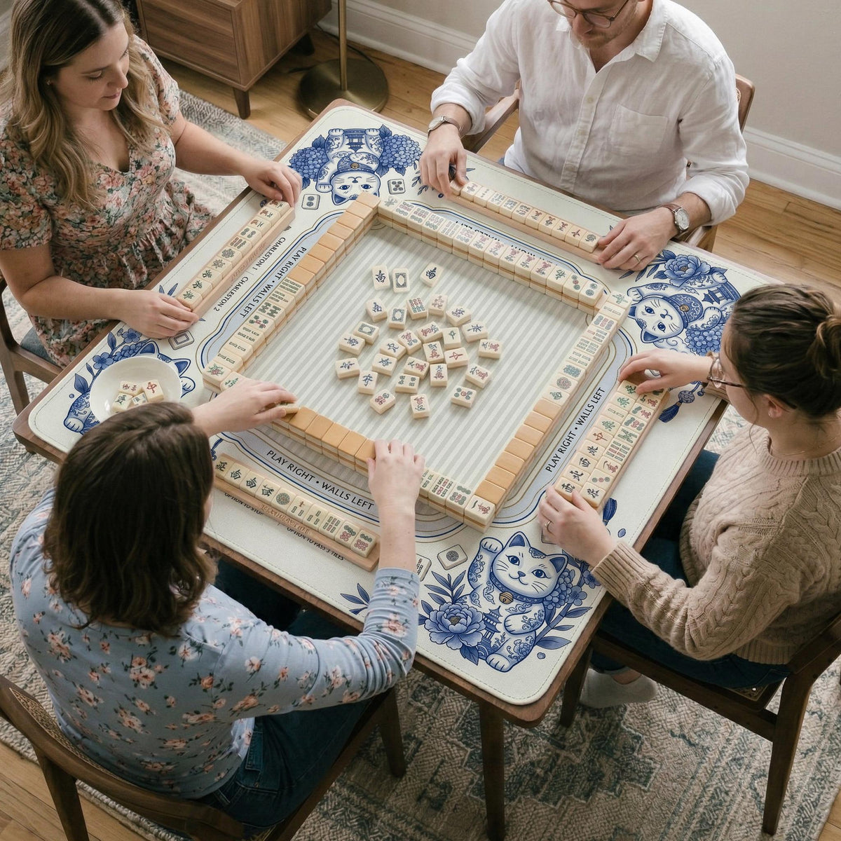 Blue and white square mahjong mat with lucky cat artwork, floral chinoiserie pattern, tile icons, and a rule guide layout.