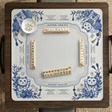 Blue and white square mahjong mat with lucky cat artwork, floral chinoiserie pattern, tile icons, and a rule guide layout.