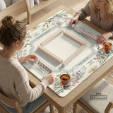 Beige square mahjong mat with a sage border, crane birds, bamboo, flowers, tile icons, and printed rules around a clean center play area.