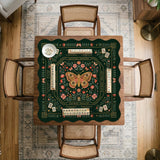 Dark botanical mahjong table mat with a floral border, large moth and butterfly design in the center, gold corner frame, and printed rules layout around the edge.
