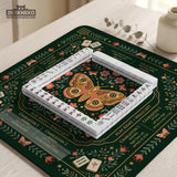 Dark botanical mahjong table mat with a floral border, large moth and butterfly design in the center, gold corner frame, and printed rules layout around the edge.