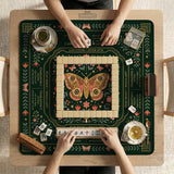 Dark botanical mahjong table mat with a floral border, large moth and butterfly design in the center, gold corner frame, and printed rules layout around the edge.