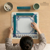 Blue and white mahjong table mat with a floral border, small birds, pagoda details, striped center, and printed rules around the edge.