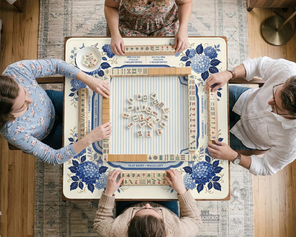 Blue and white mahjong table mat with a floral border, small birds, pagoda details, striped center, and printed rules around the edge.