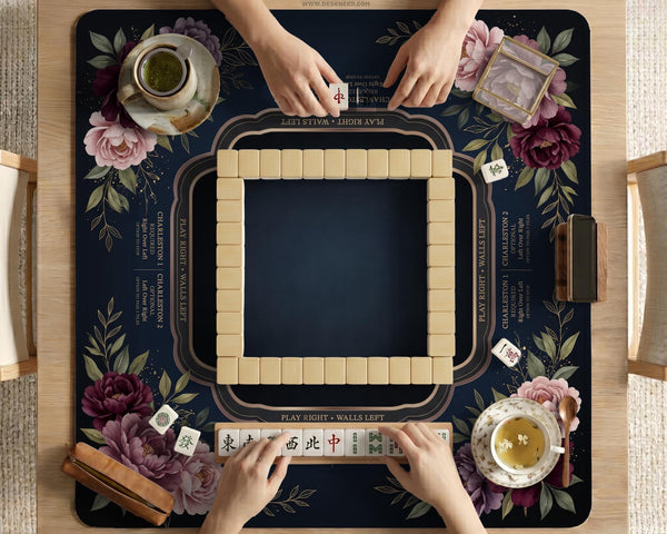 Burgundy mahjong mat with a floral border, gold botanical details, and printed American Mahjong rules on a dark background.