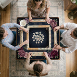 Burgundy mahjong mat with a floral border, gold botanical details, and printed American Mahjong rules on a dark background.