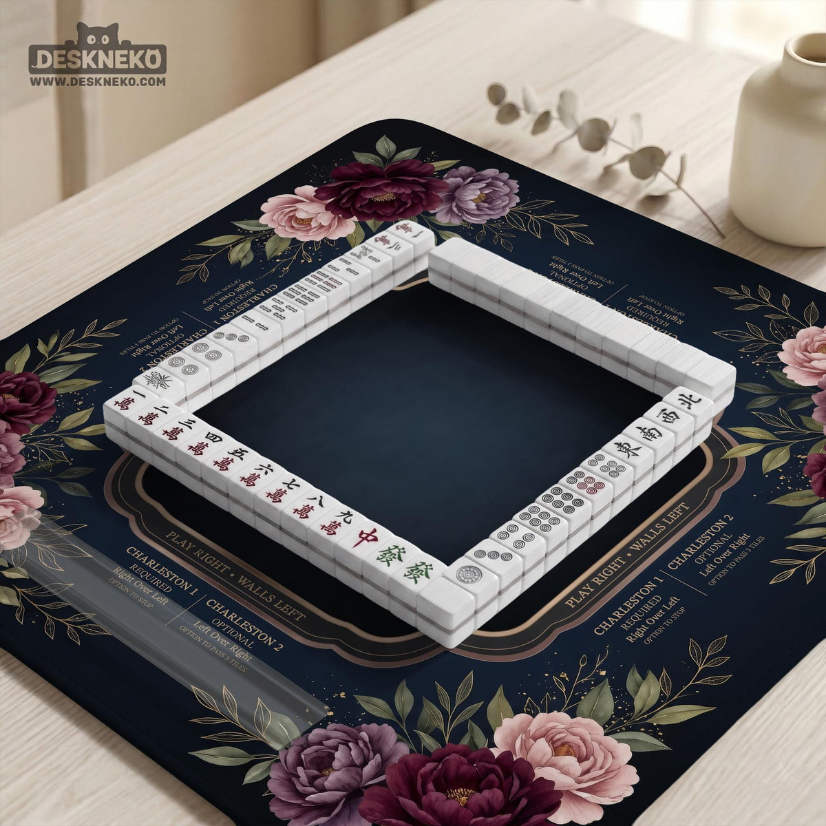 Burgundy mahjong mat with a floral border, gold botanical details, and printed American Mahjong rules on a dark background.