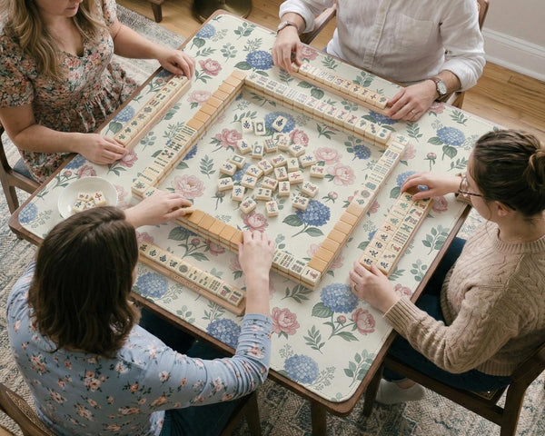 Pink floral mahjong table mat with peonies, blue hydrangeas, sage green leaves, and an ivory background.