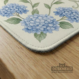 A square mahjong mat with blue hydrangea flowers, green vines, a cream background, a striped center, and printed rules around the border.