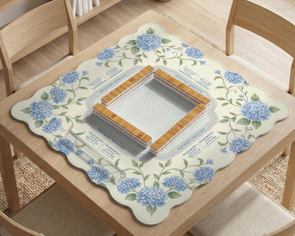 A square mahjong mat with blue hydrangea flowers, green vines, a cream background, a striped center, and printed rules around the border.