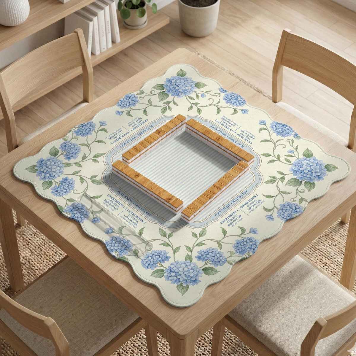 A square mahjong mat with blue hydrangea flowers, green vines, a cream background, a striped center, and printed rules around the border.