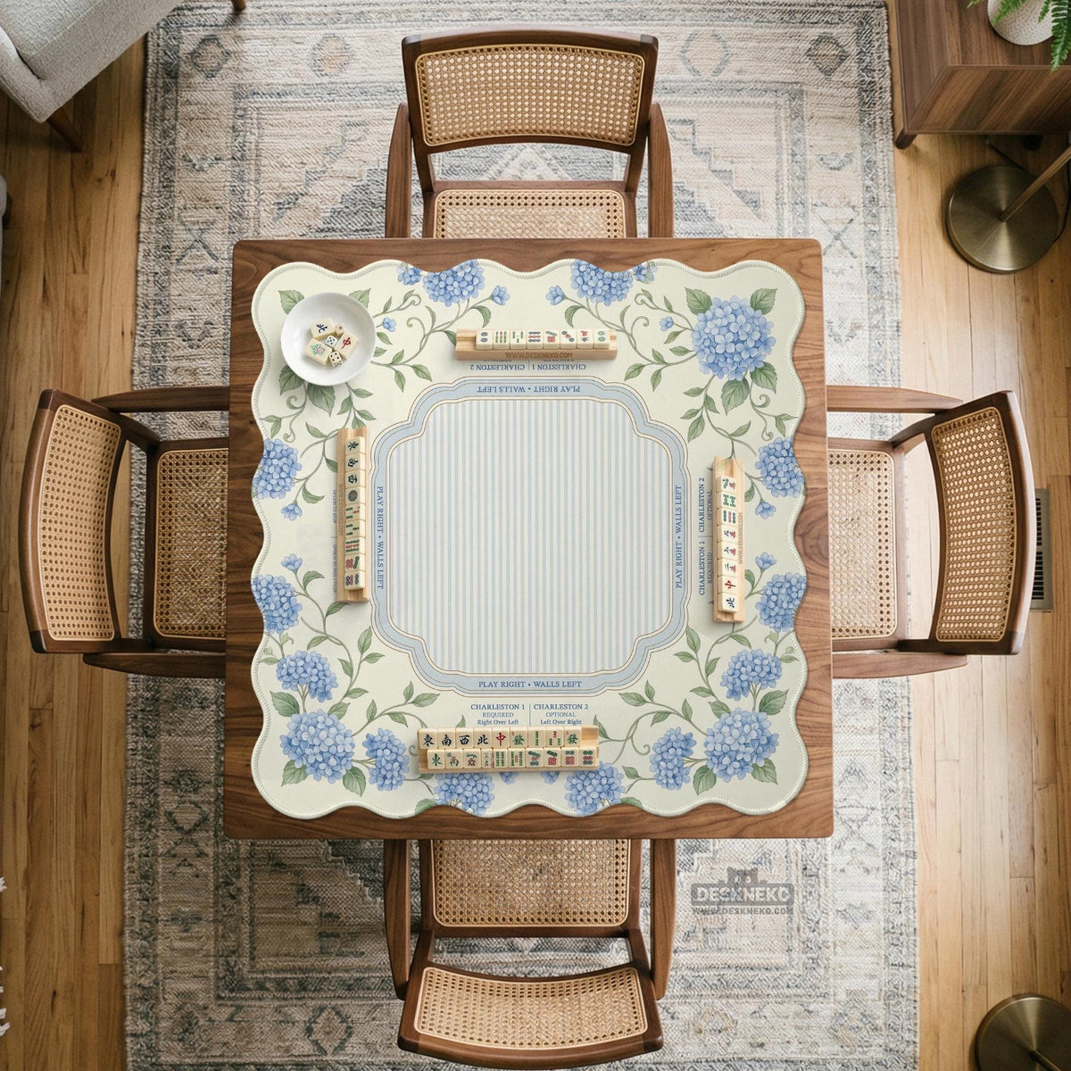 A square mahjong mat with blue hydrangea flowers, green vines, a cream background, a striped center, and printed rules around the border.