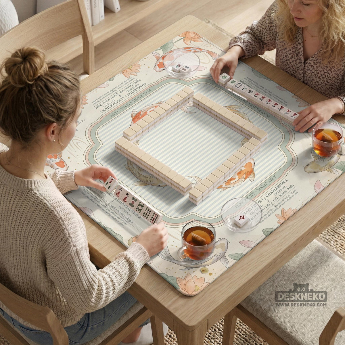 Sage and cream mahjong mat with a koi fish pond pattern, lotus blooms, water ripples, and printed instructions around the border. One version has a scalloped edge.