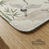 Sage green scalloped mahjong mat with bamboo, crane, and blossom illustration and printed rules around the border.