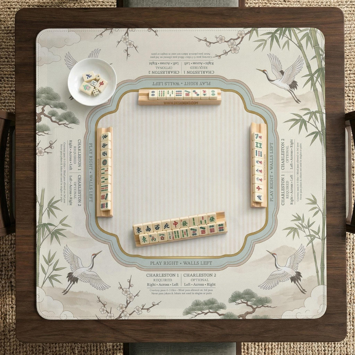 Sage green scalloped mahjong mat with bamboo, crane, and blossom illustration and printed rules around the border.