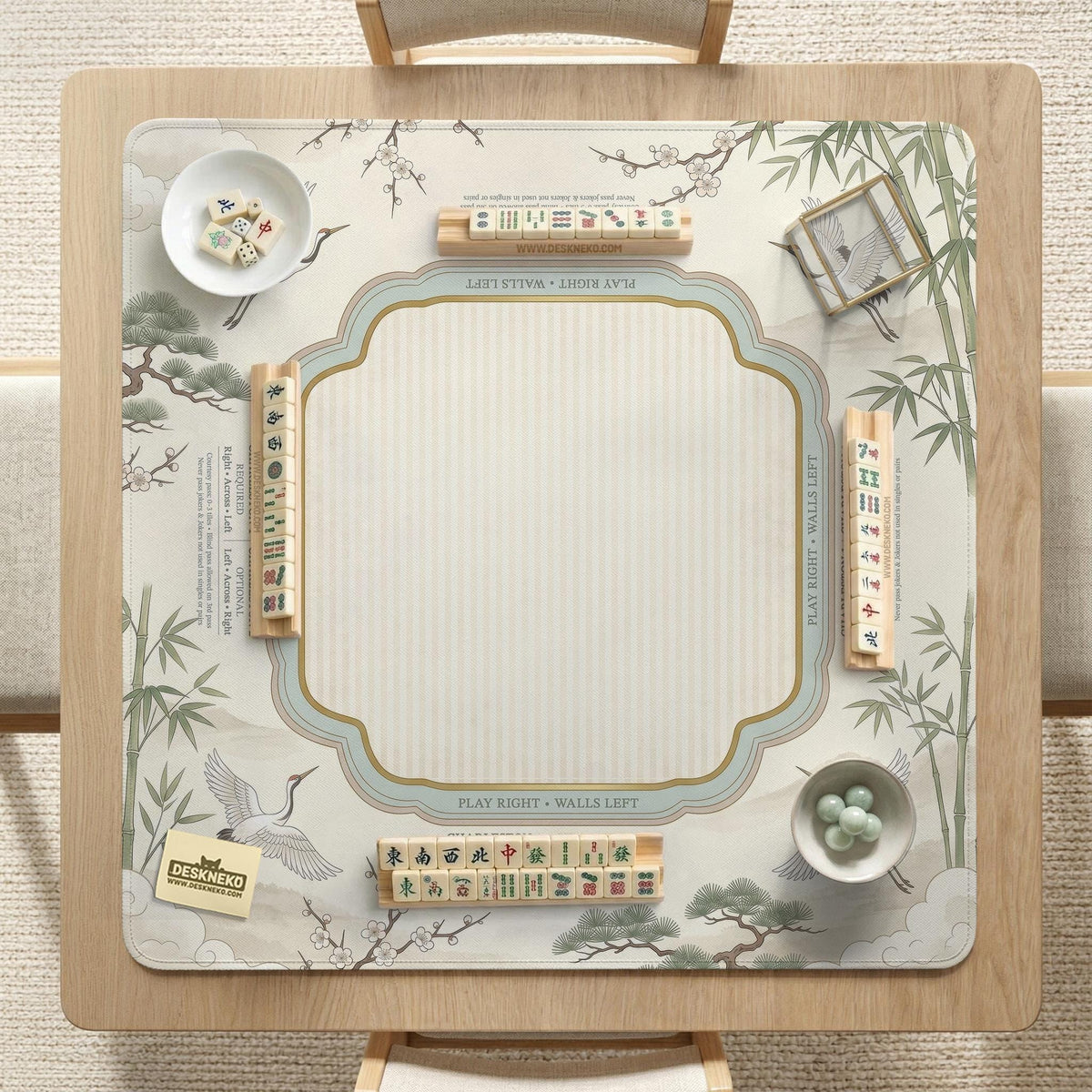 Sage green scalloped mahjong mat with bamboo, crane, and blossom illustration and printed rules around the border.