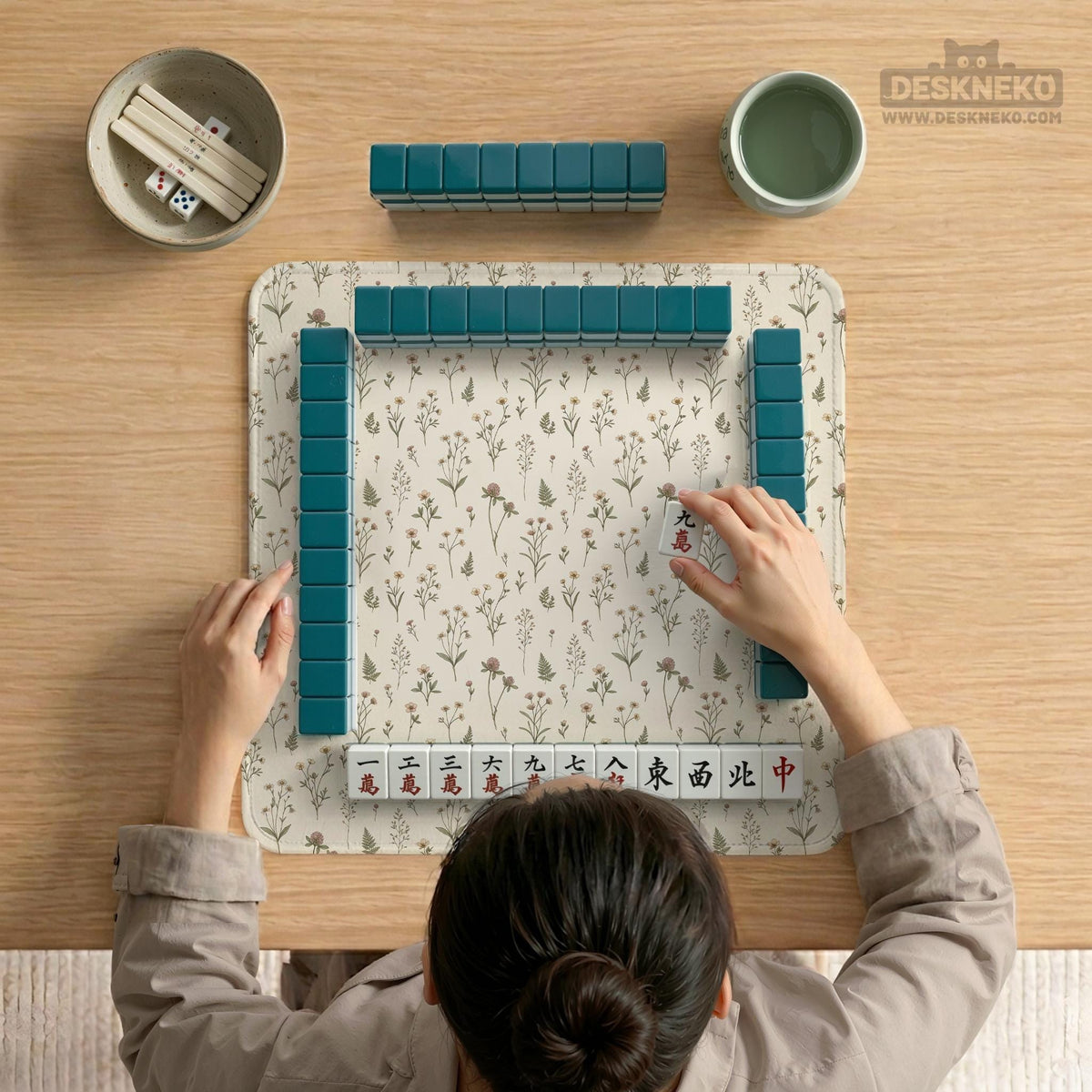 Cream mahjong mat with a floral pattern of small wildflowers and sage leaves, shown with a scalloped edge on a light neutral background.