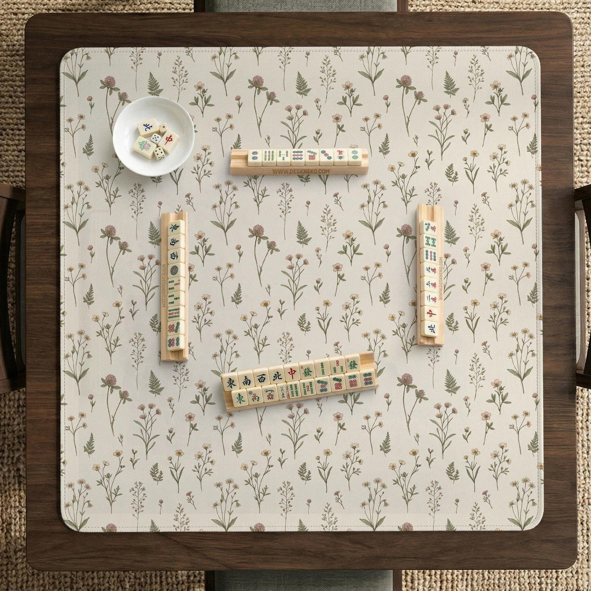 Cream mahjong mat with a floral pattern of small wildflowers and sage leaves, shown with a scalloped edge on a light neutral background.