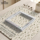 Cream mahjong mat with a floral pattern of small wildflowers and sage leaves, shown with a scalloped edge on a light neutral background.